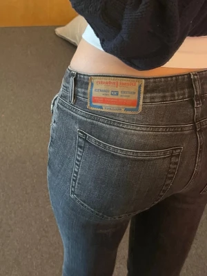 Mörkgrå bootcut jeans från Diesel - Bootcut-jeans med låg midja från Diesel i slim fit med bohemisk känsla. Figurnära från höft till knä och utsvängda nedtill. Tillverkade i stretchdenim med mörkgrå tvätt och ljusa behandlingar för ett mjukt, tvättat uttryck. Knappt använda, mycket bra skick. Supersnygga trendiga jeans som jag älskar!!💕