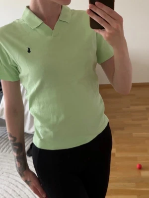 Ljusgrön pikétröja från Polo Ralph Lauren - Snygg ljusgrön pikétröja från Polo Ralph Lauren med klassisk krage och korta ärmar. Tröjan har den ikoniska loggan broderad på bröstet och är gjord i mjuk bomull. Perfekt till jeans eller shorts för en clean look.