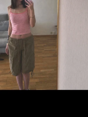 Beiga loose cargo shorts med snörning - Säljer ett par beiga loose-fit cargo shorts med snörning i midjan och vid bensluten. Shortsen har flera fickor och är perfekta för en avslappnad stil. Sköna och praktiska för varma dagar.