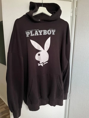Svart hoodie från Playboy x missguided - Svart oversized hoodie från Playboy med stor vit logga och text på bröstet. Klassisk känguruficka framtill och huva. Tillverkad i mjukt bomullsmaterial som är perfekt för en chill och avslappnad stil.
