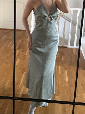 Ljusgrön långklänning från Zara - Säljer en ljusgrön långklänning med smala axelband och snygg cut-out detalj framtill. Klänningen har en v-ringad urringning och är tillverkad i ett mjukt, lätt material som ger ett fint fall. Perfekt för sommarens alla tillfällen! Helt ny!