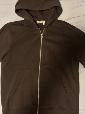 Svart hoodie med dragkedja från Weekday - Svart hoodie från Weekday i storlek M. Modellen har dragkedja framtill, två stora fickor och en klassisk huva. Tillverkad i mjukt bomullsmaterial som är skönt mot huden. Perfekt för en avslappnad och stilren look.