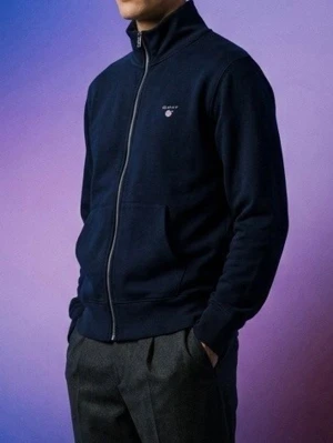 Mörkblå zip hoodie från Gant - Mörkblå hoodie från Gant med dragkedja framtill och två fickor. Klassisk design utan huva och med liten Gant-logga på bröstet. Tillverkad i mjukt material, perfekt för en avslappnad stil.