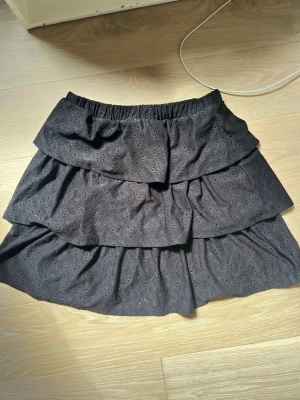 Svart volangkjol från VILA - Supersöt svart kortkjol från VILA med flera volanger och broderade detaljer. Säljer eftersom den inte kommer till andvändning. Inga tecken på andvändning från kjolen. Pris går att diskutera 💞