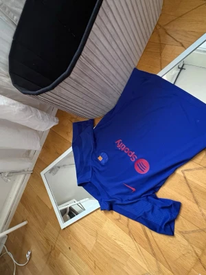 Blå FC Barcelona matchtröja Nike - Snygg blå FC Barcelona matchtröja från Nike med korta ärmar. Tröjan har klubbmärke och sponsorlogga i rött framtill samt Nike-logga. Tillverkad i lätt och ventilerande funktionsmaterial, perfekt för träning eller match.
