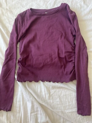 Vinröd ribbad långärmad topp - Säljer en vinröd ribbad topp med lång ärm och croppad passform. Toppen har vågig kant nertill och är tillverkad i ett mjukt stretchigt material. Perfekt att styla med jeans eller kjol för snygg look😻