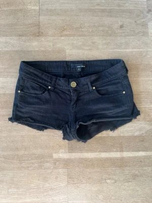 Svarta jeansshorts från Tally Weijl - Säljer ett par svarta jeansshorts från Tally Weijl i storlek 36. De har låg midja, råa kanter och klassisk femficksdesign med knapp och dragkedja framtill. Perfekta för varma dagar och en avslappnad look.