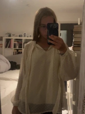 Ljus cremefärgad blus med prickar - Säljer en luftig cremefärgad blus med diskreta prickar och v-ringning. Blusen har långa, transparenta ärmar med resår vid handlederna och ett tunt, lätt material som ger ett romantiskt intryck. Perfekt att styla med jeans eller kjol. Storlek står inte men skulle gissa runt XS/S.
