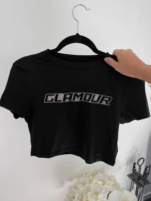 Svart croppad t-shirt med strass - En svart croppad t-shirt med strass. Säljer pga att den aldrig kom till användning 🤍 Liten i storleken då den passar mig som har S. Passar även till M 💞  (ALDRIG ANVÄND)  Längd: 40 cm Axel: 39 cm Byst: 88 cm 