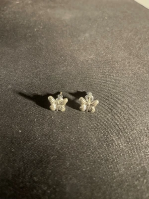 Söta fjärilsörhängen i silverfärg - Små örhängen i form av fjärilar med detaljerad design. De är silverfärgade och perfekta för dig som gillar diskreta men unika accessoarer. Passar till alla tillfällen och är lätta att matcha med andra smycken. OBS! Materialet är okänt, kan ej garantera att det är rostfritt.