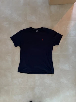 Mörkblå t-shirt från Ralph Lauren - Klassisk mörkblå t-shirt från raffe säljes! Perfekt till det varmare vädret! Dessutom om du vill sticka ut från de andra😀 nypris~1200 fint skick dvs inga defekter, hör av dig vid frågor//avenue