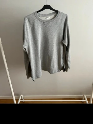 Grå basic sweatshirt från Cubus  - En stilren grå sweatshirt från Cubus i mjukt bomullsmaterial. Tröjan har rund halsringning, långa ärmar och ribbade muddar vid ärmslut och nederkant. Perfekt för en avslappnad och enkel look.