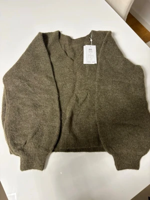 Olivgrön kofta från VILA, XL - Mysig olivgrön kofta från VILA i storlek XL. Koftan har en avslappnad passform, ballongärmar och ribbade muddar. Tillverkad i en mjuk, stickad ullblandning som passar perfekt för kyliga dagar.