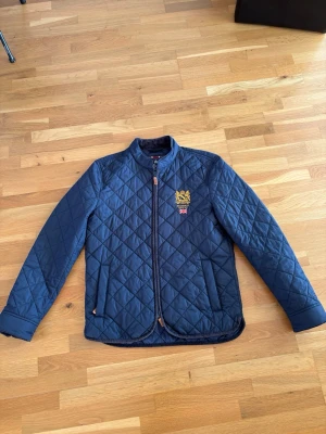 Morris jacka  - Säljer en snygg och tidlös Morris jacka. Perfekt som vår-/höstjacka. Klassisk design med dimantmösnter, dragkedja framtill och praktiska fickor