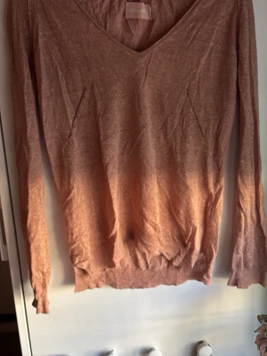 Ljusbrun stickad tröja från Zadig Voltaire - Säljer en tunnstickad ljusbrun tröjamed v-ringning och långa ärmar. Tröjan har diskreta håldetaljer framtill och ribbade muddar vid ärmslut och nederkant. 