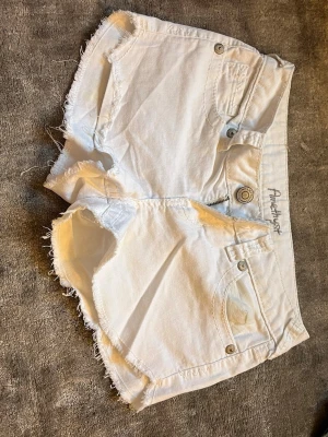 Vita jeansshorts  - Säljer ett par vita jeansshorts från Amethyst med råa kanter och klassisk femficksdesign. Shortsen har knappgylf motsvarar storlek 36