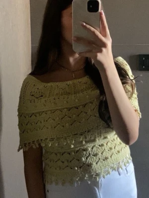 Gul virkad offshoulder topp - Söt gul virkad topp med offshoulder-design och fina virkade detaljer. Toppen har en croppad passform och dekorativa kanter. Perfekt för dig som vill ha en unik och somrig stil.