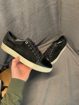 Lanvin Cap toe - Snygga svarta Lanvin Cap Toe från Lanvin med ovandel i mocka och lackdetaljer på tån. Nypris ca 5000 skorna är i storlek skorna har tecken på användning och är en aning skev i hälsenan. (Syns och känns inte, men kan skicka bild vid frågan). storlek uk 8 vilket motsvarar storlek 42.                                                              Skriv vid frågor, pris kan diskuteras🤝