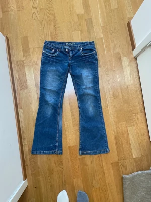 Blå lowwaist bootcut jeans - Säljer ett par blå bootcut jeans med snygga slitningar. Jeansen har låg midja och är tillverkade i stretchig denim för skön passform. Lowwaist bootcut. Använda 3 ggr. Pris kan diskuteras vid snabb affär💗