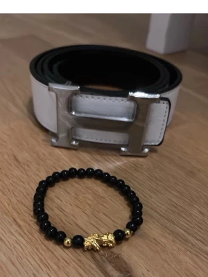 Vitt  bälte med silverdetalj - Snyggt vitt bälte med stor, ikonisk H-spänne i silver. Pris kan diskuteras vid nabb affär, 120cm