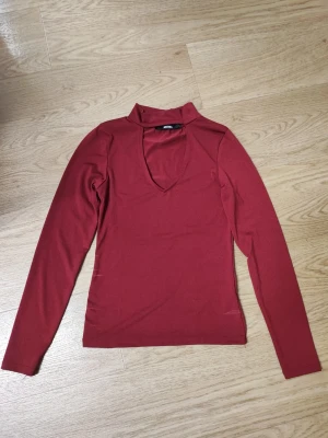 Vinröd långärmad topp - Trendig vinröd långärmad topp från Bik Bok med v-ringad öppning framtill. Tunn och stretchig modell som sitter snyggt