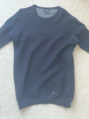 Mörkblå stickad tröja  - Snygg mörkblå stickad tröja från Lindbergh med diskret ribbad struktur. Tröjan har rund halsringning och långa ärmar, perfekt för lager på lager. Passar till både jeans och chinos för en clean look.