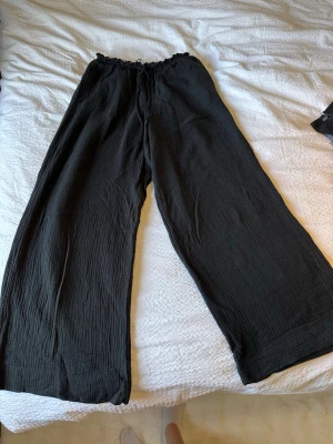 Svarta byxor med vida ben från GinaTricot  - Snygga svarta byxor från GinaTricot med breda, raka ben och resår i midjan. Materialet är lätt och luftigt. Använda ett par gånger. 