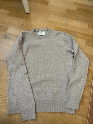 Beige stickad tröja These Glory Days - Säljer en stilren beige stickad tröja från These Glory Days. Tröjan har rund halsringning, ribbade muddar och är tillverkad i ett mjukt, tunt stickat material. Perfekt för lager på lager och enkel att matcha med olika outfits.