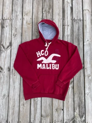 Sällsynt Hollister Malibu röd hoodie - Röd Malibu Hollister hoddie i nyskick. Tröjan är väldigt sällsynt och finns inte många i denna färgen. Size Medium. Hör gärna av er vid intresse!