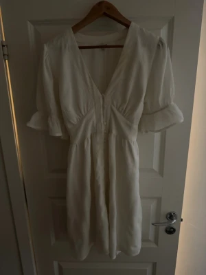 Vit klänning - Super fin vit klänning som använts en gång, den har knappar framtill och snörren man kan knyta åt i midjan bak eller framtill. Den passar superbra nu till midsommar eller studenten!