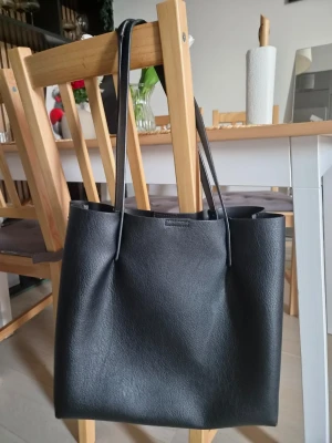 Svart axelväska från Åhlens -  svart axelväska från Åhlens. Den är använd och sömmar har gått upp, det ska dessutom finnas en "påse" som ska vara innuti väskan men hittar inte den:(