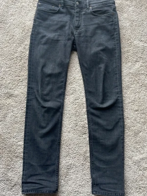 Acne Studios Jeans - Säljer ett par svarta/mörkgråa slim-fit jeans ifrån Acne. Jeansen är köpta på Ströms i Stockholm och är uppsydda från längd 34 till att passa cirka längd 32. Endast använda 3 gånger och är i perfekt skick! Nypris 3000kr. Hör av dig vid minsta fundering😁