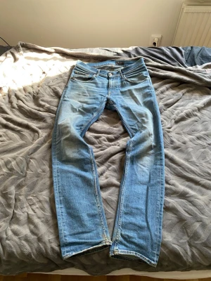 Tiger of Sweden jeans  - Säljer ett par ljusblå jeans med rak passform och klassisk femficksdesign. Jeansen har normal midja och är tillverkade i denim med snygga slitningar framtill. Perfekta för en avslappnad och trendig look. Slitningar på sista bilden men de syns inte när man har på sig dom