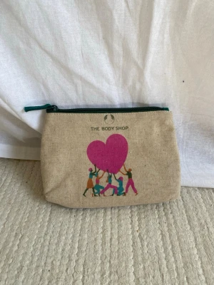 Necessär  - Söt necessär från The Body shop. Aldrig använd. Höjd: 13cm, längd: 20,5cm
