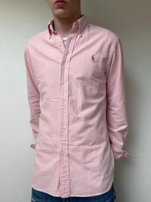 Ljusrosa skjorta från Ralph Lauren - Ijusrosa skjorta från Ralph lauren i storlek Medium. Modellen är 178 och väger cirka 70kg men rekommenderar att man ska vara 180-185 för denna skjortan!
