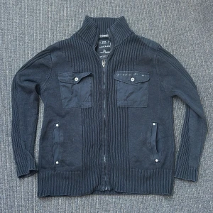 Svart stickad cardigan  - Snygg svart stickad cardigan från Casa Blanca med dragkedja och ribbade detaljer. Jackan har två bröstfickor med knappar och en hög krage. Perfekt för kyliga dagar! Fungerar sjukt bra till skolan osv. 