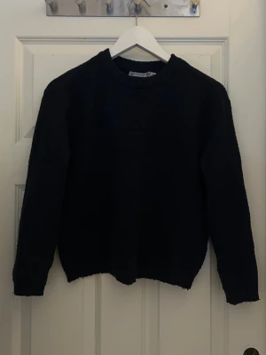 Mörkblå stickad tröja - En enkel och stilren mörkblå stickad tröja med rund halsringning och långa ärmar. 