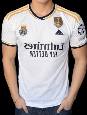 Real Madrid matchtröja Bellingham - Säljer en vit Real Madrid matchtröja från Adidas med Bellingham och nummer 5 på ryggen. Tröjan har guldfärgade detaljer på axlarna, klubbmärke och sponsorlogga på framsidan samt patch på ärmen. Perfekt för fotbollsfans som vill representera sitt lag.