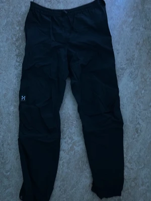 Svarta cargobyxor från Haglöfs - Säljer ett par svarta cargobyxor från Haglöfs med klassisk passform och praktiska fickor på sidorna. Byxorna har en diskret Haglöfs-logga på benet och är tillverkade i slitstarkt material, perfekta för en aktiv livsstil.