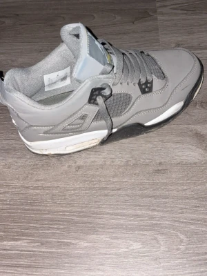 Gråa Retro sneakers - Säljer ett par gråa  sneakers med meshdetaljer och vita samt svarta inslag på sulan. Skorna har klassisk snörning, Jumpman-logga på plösen och coola plastdetaljer vid snörningen. Ovandelen är i mocka och textil för en stilren look.