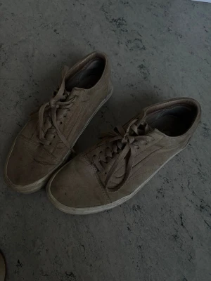 Suede vans - Säljer ett par beigea Vans sneakers i mocka med klassisk låg siluett och snörning. Skorna har vit sula och diskret sidestripe. Perfekta för dig som gillar en clean och stilren look.