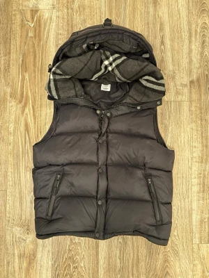 Burberry väst jacka - Säljer en svart pufferjacka från Burberry med avtagbara ärmar så den kan användas som väst. Kommer med tags. Storlek L men passar även M.