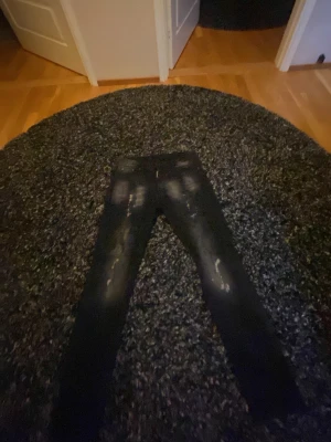 Svarta slitna jeans från Dsquared2 - Säljer ett par svarta jeans från Dsquared2 med slitningar och distressed detaljer. Jeansen har smal passform och klassisk femficksdesign. Perfekta för dig som gillar en edgy och trendig stil.