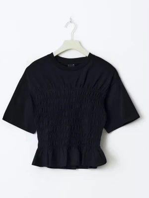 Svart smockad topp med volang - Trendig svart topp med smockad midja och volangkant nedtill. Toppen är ifrån Ginatricot.