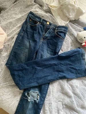 Highwaist Blå bootcut jeans med slitningar - Denim bomull jeans, dom är högmidjade och stl 34, passar S/xs  osäker vilket märke därav priset