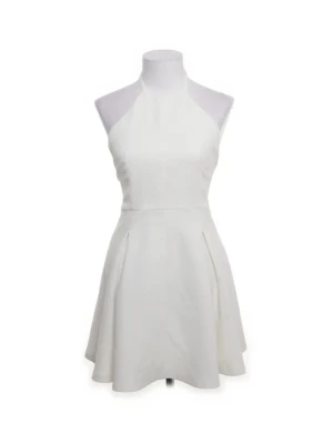 Vit halterneckklänning från Zara - Snygg vit kortklänning från Zara Trafaluc Collection med halterneck och utsvängd kjol. Klänningen är ärmlös och har en stilren, minimalistisk design som passar perfekt till varma dagar. Tillverkad i ett mjukt material som känns bekvämt mot huden.