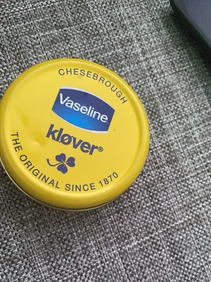 Vaseline Klöver läppbalsam 40g - Klassiskt läppbalsam från Vaseline Kløver i en rund gul plåtburk. Innehåller petrolatum som mjukgör och skyddar läpparna. Perfekt att ha med i väskan för återfuktade läppar hela dagen.