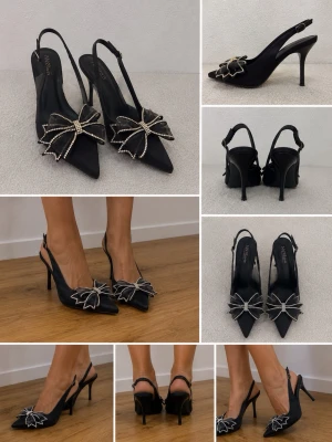 Svarta pumps med strassrosett - Supersnygga svarta pumps från INN99 med spetsig tå och öppen häl. Skorna har en stor rosett framtill dekorerad med glittrande strass, vilket ger en extra glamorös touch. Perfekta för dig som vill sticka ut med elegans och stil.