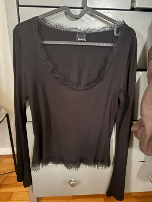 Svart långärmad topp med spets - Säljer en svart långärmad topp från Gina Tricot med snygga spetsdetaljer vid halsringningen och nederkanten. Toppen har en rundad urringning och är i ett mjukt material.
