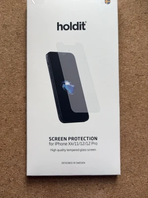 Holdit skärmskydd - Skärmskydd i härdat glas från Holdit, anpassat för iPhone XR, 11, 12 och 12 Pro. Ultratunt med 0,33 mm tjocklek och 9H hårdhet. Skyddar mot repor och stötar. Transparent och designat i Sverige. Enbart varit i en låda men kartongen är lite uppriven